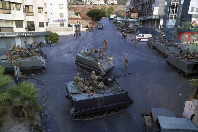 Lebanese army soldiers sit on their armored vehicles as they deployed to contain the tension after heavy fire in the coastal town of Khaldeh, south of Beirut, Lebanon, Sunday, August 1, 2021. At least two people were killed on Sunday south of the Lebanese capital when gunmen opened fire at the funeral of a Hezbollah commander who was killed a day earlier, an official from the group said. (Photo by Bilal Hussein/AP Photo)
