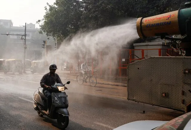 A scooter passes by an anti-smog gun being used to reduce pollution, on a smoggy morning in the old quarters of Delhi, India on November 17, 2023. (Photo by Anushree Fadnavis/Reuters)