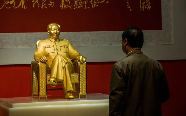 A man looks at a gold and jade statue of Mao Zedong displayed at an exhibition in Shenzhen, south China's Guangdong province on December 13, 2013. The statue, worth more than 16 million USD was unveiled on December 13, in the latest example of Communist China's indecision over how to commemorate its founding father's 120th anniversary. (Photo by AFP Photo)