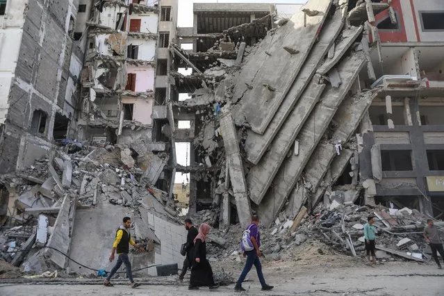 Palestinians walk through destruction in Gaza City on Friday, November 24, 2023, as the temporary ceasefire between Israel and Hamas took effect. (Photo by Mohammed Hajjar/AP Photo)