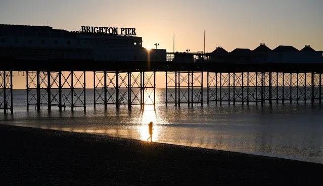 A walker enjoys the sunny but freezing weather by Brighton Pier at sunrise on December 1, 2023 after the coldest night of the season so far throughout Britain. (Photo by Simon Dack/Alamy Live News)