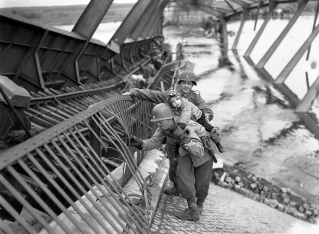 Captain J McMahon, of the US 9th Army, carrying a child over a bombed bridge at the River Elbe, Tangemunde, 1st May 1945. The bridge was blown up by retreating German troops. (Photo by Fred Ramage/Keystone/Getty Images)