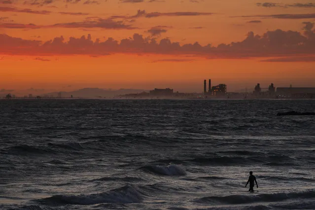 A man wades into the ocean at sunset, Tuesday, June 22, 2021, in Newport Beach, Calif. (Photo by Jae C. Hong/AP Photo)