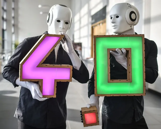 Two actors dressed as roboters hold up an illuminated 4 - 0 lettering at the “Leaders Dialogue – Industry 4-0 Made in Germany” during the launch of the “Industry 4-0” platform at the Hannover Messe industrial trade fair in Hanover, central Germany on April 14, 2015. India is the partner country of this year's trade fair running until April 17, 2015. (Photo by Ole Spata/AFP Photo/DPA)