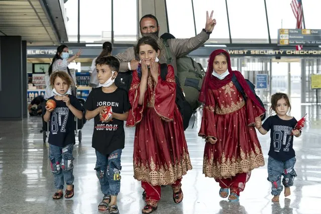 Families evacuated from Kabul, Afghanistan, walk through the terminal before boarding a bus after they arrived at Washington Dulles International Airport, in Chantilly, Va., on Friday, August 27, 2021. (Photo by Jose Luis Magana/AP Photo)