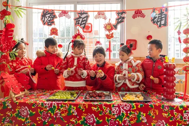 Children learn to make 'ice-sugar gourd' from their teacher at a kindergarten as the New Year approaches on December 22, 2023 in Hefei, Anhui Province of China. (Photo by Zhao Ming/VCG via Getty Images)