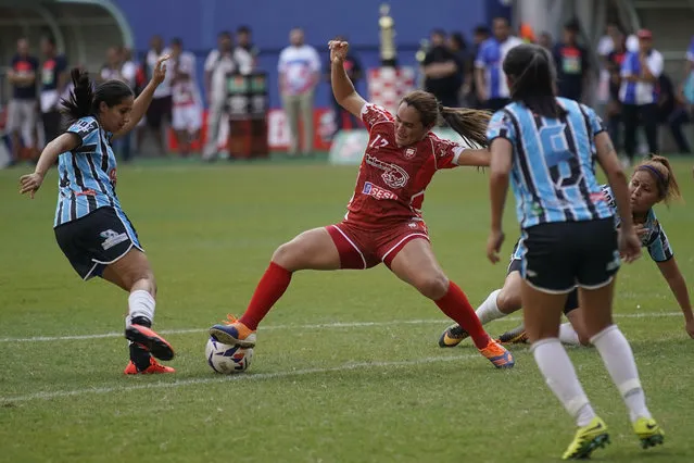 Salcomp striker Suzy Carvalho, center, battles for the ball with Gremio players at Arena da Amazonia in Manaus, Brazil, Saturday, February 16, 2019. The Salcomp factory workers, who'd worked a full shift before the game, looked tired playing Gremio whose players had been able to rest before the match began. Then, the momentum began to shift in Salcomp's favor. “It was the God of soccer intervening for us”, Carvalho said. (Photo by Victor R. Caivano/AP Photo)