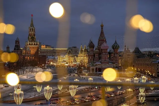 The Spasskaya Tower, Red Square, the GUM department store and the St. Basil's Cathedral are decorated for the New Year and Christmas festivities are seen though a window of the Hotel Baltschug Kempinski Moscow in Moscow, Russia, on Tuesday, December 26, 2023. (Photo by Alexander Zemlianichenko/AP Photo)