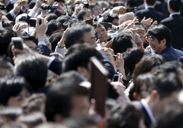 Japan's Prime Minister Shinzo Abe (R) greets guests during a cherry blossom viewing party at Shinjuku Gyoen park in Tokyo April 18, 2015. (Photo by Issei Kato/Reuters)
