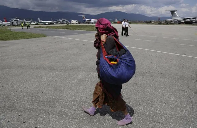 A woman walks barefooted towards the hold area after she was evacuated at the airport in Kathmandu, Nepal, Monday, April 27, 2015. (Photo by Altaf Qadri/AP Photo)