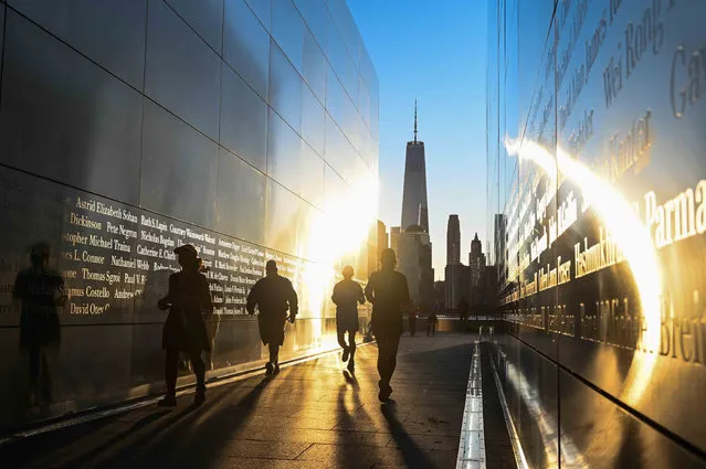 Visitors walk at sunrise at the Empty Sky 9/11 Memorial in Liberty State Park in Jersey City, New Jersey on September 11, 2021. The memorial shows some of the names of the people that died on the September 11, 2001 terrorist attack in New York City. (Photo by Roberto Schmidt/AFP Photo)