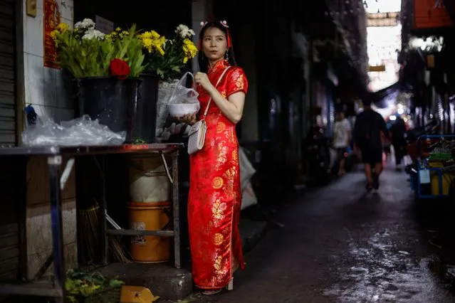 A woman eats while standing in an alley during Lunar New Year's Eve in Bangkok's Chinatown, Thailand, on February 9, 2024. (Photo by Jorge Silva/Reuters)