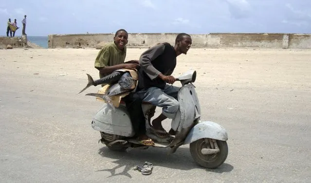 A Somali boy carries swordfish as he rides on a Vespa scooter taxi in southern Mogadishu, Somalia, in this August 16, 2010 file photo. Scooter maker Piaggio is expected to report Q1 results this week. (Photo by Feisal Omar/Reuters)