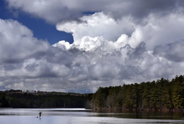 Storm clouds build prior to the arrival of a thunderstorm as Jeff Warren of Auburn, Maine, heads for shore on his paddleboard on Lower Range Pond Thursday, March 17, 2016, in Poland, Maine. (Photo by Robert F. Bukaty/AP Photo)