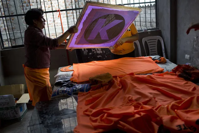 In this March 30, 2016 photo, workers create flags for Keiko Fujimori's presidential campaign in Ayacucho, Peru. The bright orange campaign signs plastered on walls and houses promoting presidential hopeful Keiko Fujimori are an emblem of the impoverished community’s continued loyalty to the candidate’s father, imprisoned former president Alberto Fujimori, who the corn and potato farmers here credit with beating back a Maoist-inspired rebel group that slaughtered their parents and children during a brutal armed conflict. (Photo by Rodrigo Abd/AP Photo)