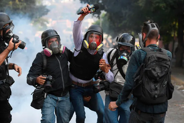Venezuelan VPITV journalist Gregory Jaimes (C) is assisted by colleagues after being injured during clashes of anti-government protesters and security forces during the commemoration of May Day on May 1, 2019 after a day of violent clashes on the streets of the capital spurred by Venezuela's opposition leader Juan Guaido's call on the military to rise up against President Nicolas Maduro. Guaido called for a massive May Day protest to increase the pressure on Venezuelan President Nicolas Maduro. (Photo by Federico Parra/AFP Photo)