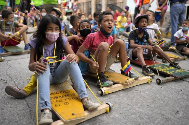 Children enjoy and participate in a traditional street race of “carruchas”, the name for makeshift wooden cars in Caracas, Venezuela, Saturday, December 18, 2021. Children enjoyed the race marking 10 years of persevering this tradition. (Photo by Ariana Cubillos/AP Photo)
