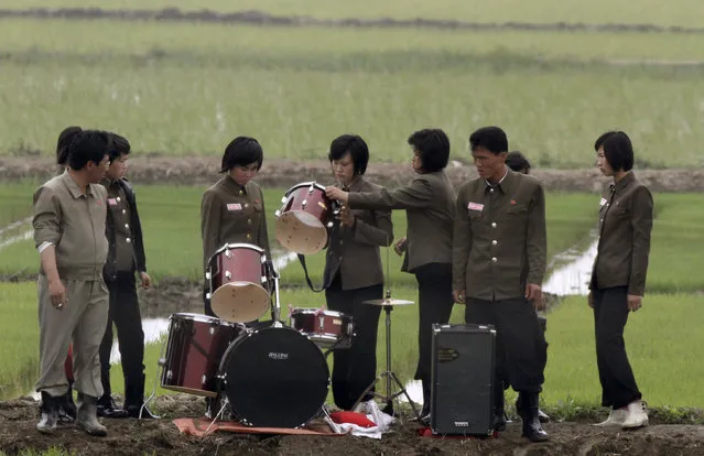 Members of a music group check a drum on a path amid fields as they pack up their instruments after giving a performance to greet the farmers at Hwanggumpyong Island, near the North Korean town of Sinuiju and the Chinese border city of Dandong June 6, 2012. (Photo by Jacky Chen/Reuters)