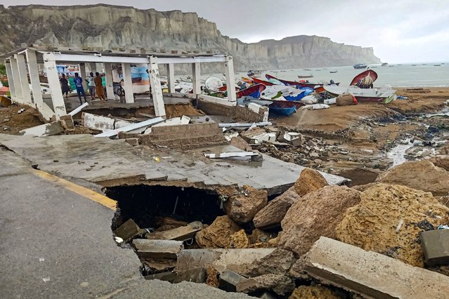 Fishermen gather under a faulty structure along a damaged roadside, as boats are stacked near a jetty following heavy rainfall in Gwadar in Balochistan province on April 18, 2024. At least 65 people have died in storm-related incidents including lightning in Pakistan, officials said, with rain so far in April falling at nearly twice the historical average rate. (Photo by AFP Photo)