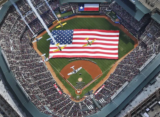 Vintage planes from the Cavanaugh Flight Museum flyover Globe Life Park during opening day ceremonies before a baseball game between the Texas Rangers and Philadelphia Phillies in Arlington, Texas, Monday, March 31, 2014. (Photo by Louis DeLuca/AP Photo/The Dallas Morning News)