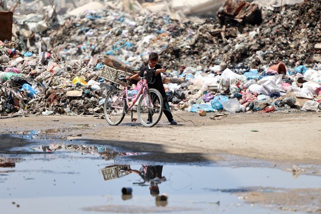 A Palestinian child pushes a bicycle past a rubbish dump in Gaza City on May 3, 2024, amid the ongoing conflict between Israel and the militant group Hamas. (Photo by AFP Photo/Stringer)
