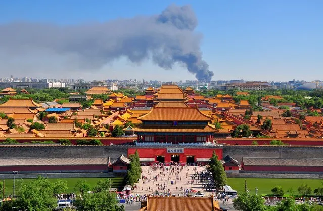 The Palace Museum is seen in the foreground as smoke rises from a fire in a timber yard in Beijing, China, June 30, 2015. No casualty has been reported, according to local media. (Photo by Reuters/Stringer)