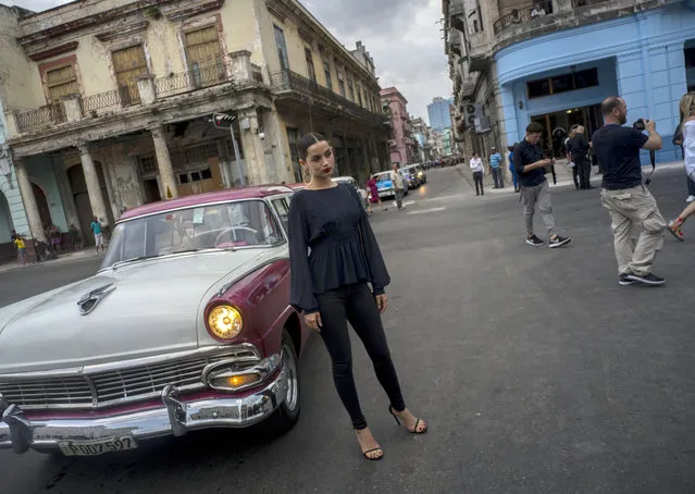 A model poses in front of a vintage American car as she arrives to the presentation of fashion designer Karl Lagerfeld's “cruise” line for fashion house Chanel, at the Paseo del Prado street in Havana, Cuba, Tuesday, May 3, 2016. With the heart of the Cuban capital effectively privatized by an international corporation under the watchful eye of the Cuban state, the premiere of Chanel 2016/2017 “cruise” line offered a startling sight in a country officially dedicated to social equality and the rejection of material wealth. (Photo by Ramon Espinosa/AP Photo)