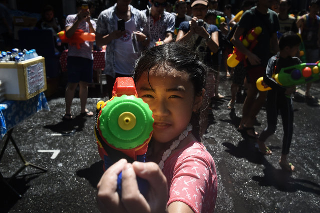 A girl aims a water pistol at the camera during Songkran, Thailand' s traditional New Year festival, on Silom road in Bangkok on April 13, 2017. (Photo by Lillian Suwanrumpha/AFP Photo)