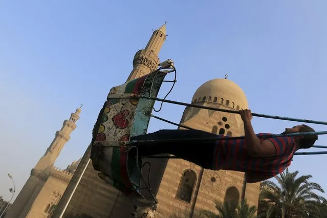 An man plays on swing near a cemetery during Eid al-Fitr in the old Islamic area of Cairo, Egypt, July 17, 2015. (Photo by Amr Abdallah Dalsh/Reuters)