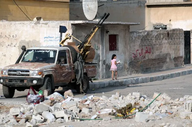 A girl walks near a truck mounted with a weapon in the border town of Tal Abyad, Syria, October 17, 2019. (Photo by Khalil Ashawi/Reuters)