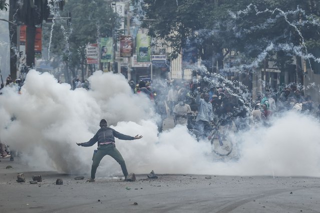 A teargas canister detonates as a protester gestures at Kenyan anti-riot police officers during anti-government protests in Nairobi on July 16, 2024. Police were out in force in the centre of Kenya's capital on Tuesday after calls for more demonstrations against the embattled government of President William Ruto. Activists led by young Gen-Z Kenyans launched peaceful rallies a month ago against deeply unpopular tax hikes but they descended into deadly violence last month, prompting Ruto to drop the planned increases. (Photo by Simon Maina/AFP Photo)