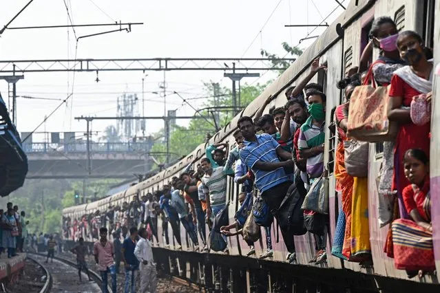 Commuters watch after their train was blocked by leftist activists at a railway station during a nationwide general strike against the policies of the central government in Kolkata on March 28, 2022. (Photo by Dibyangshu Sarkar/AFP Photo)