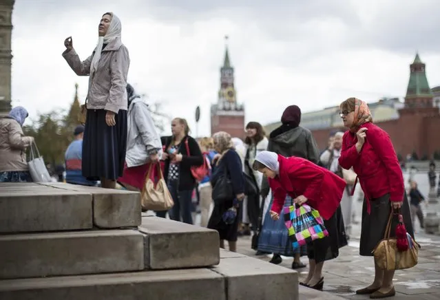People cross themselves as they leave the Church of the Kazan Mother of God in Red Square after a religion service in honor of the Kazan Icon of the Mother of God in Moscow, Russia, Tuesday, July 21, 2015, with the Kremlin Wall and Spasskaya Tower are in the background. (Photo by Alexander Zemlianichenko/AP Photo)