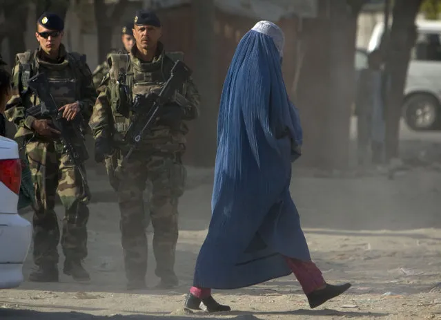An Afghan woman clad in a burqa walks past French soldiers from the NATO in Kabul April 1, 2008. (Photo by Ahmad Masood/Reuters)