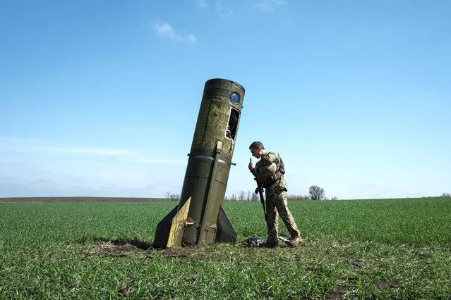 A Ukrainian serviceman looks at a Russian ballistic missile's booster stage that fell in a field in Bohodarove, eastern Ukraine, on April 25, 2022, amid the Russian invasion of Ukraine. (Photo by Yasuyoshi Chiba/AFP Photo)
