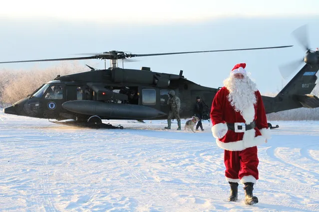 This December 3, 2019 photo shows Santa Claus arriving in Napakiak, Alaska, on an Alaska National Guard UH-60 Black Hawk helicopter. The Guard brought its Operation Santa Claus to the western Alaska community, which is being severely eroded by the nearby Kuskokwim River. (Photo by Mark Thiessen/AP Photo)