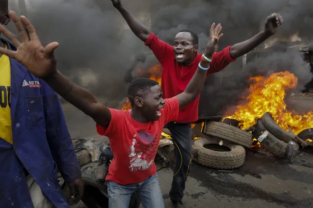 Opposition supporters react in front of a burning barricade they set up in the Kibera slum of Nairobi, Kenya, during their weekly protest against the country's electoral body Independent Electoral and Boundaries Commission (IEBC), 06 June 2016. Protests in the capital remained relatively peaceful, however, the local media reported that at least two protesters were shot dead in a protest in the western city of Kisumu. (Photo by Dai Kurokawa/EPA)