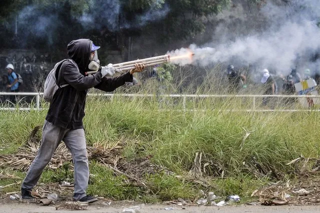 An opposition demonstrator fires an improvised weapon in a clash with riot police during the “Towards Victory” protest against the government of Nicolas Maduro, in Caracas on June 10, 2017. Clashes at near daily protests by demonstrators calling for Maduro to quit have left 66 people dead since April 1, prosecutors say. (Photo by Luis Robayo/AFP Photo)