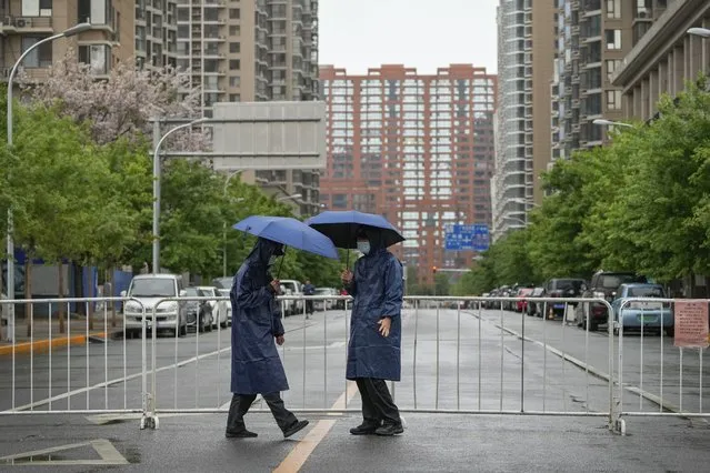 Security guards patrol along a barricaded road heading to locked-down communities on Wednesday, April 27, 2022, in Beijing. Workers put up fencing and police restricted who could leave a locked-down area in Beijing on Tuesday as authorities in the Chinese capital stepped up efforts to prevent a major COVID-19 outbreak like the one that has all but shut down the city of Shanghai. (Photo by Andy Wong/AP Photo)