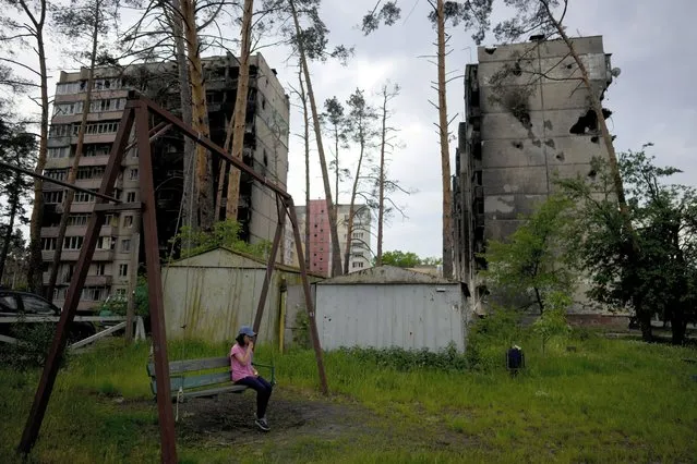 A girl sits on a swing outside destroyed buildings during attacks in Irpin outskirts Kyiv, Ukraine, Monday, May 30, 2022. (Photo by Natacha Pisarenko/AP Photo)