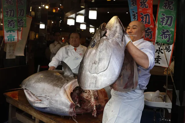 A sushi chef holds up the head of a bluefin tuna at a restaurant in Tsukji market area in Tokyo, Sunday, January 5, 2020, after it was sold at the first auction of 2020 at Tokyo's Toyosu fish market. The tuna was sold 193.2 million yen (1.8 million US dollars) Sunday. (Photo by Jae C. Hong/AP Photo)