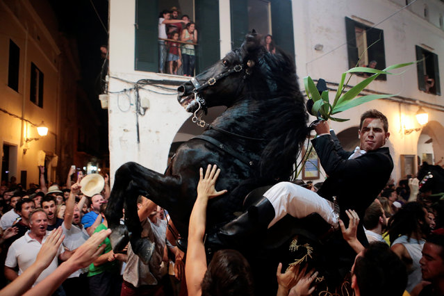 A rider rears up on his horse while surrounded by a cheering crowd during the traditional Fiesta of Sant Joan (Saint John) in downtown Ciutadella, on the island of Menorca, Spain June 23, 2016. Horse riders are representatives of ancient Ciutadella society – nobility, clergy, craftsmen and farmers. (Photo by Enrique Calvo/Reuters)