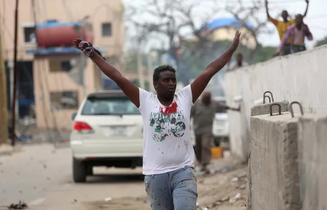 A man raises his hands as he walks from the scene of a suicide car bombing outside Nasahablood hotel in Somalia's capital Mogadishu, June 25, 2016. (Photo by Feisal Omar/Reuters)