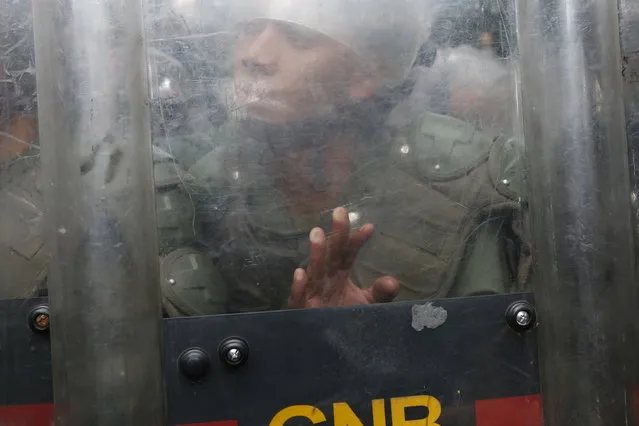 A National Guard soldier pushes his shield against members of the press and opposition lawmakers inside the grounds of the National Assembly in Caracas, Venezuela, Tuesday, January 7, 2020. Venezuelan opposition leader Juan Guaidó and lawmakers who back him pushed their way into the legislative building on Tuesday following an attempt by rival legislators to take control of the congress. (Photo by Andrea Hernandez Briceño/AP Photo)