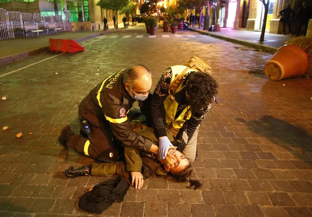 Civil defense workers treat an injured protester injured during a protest where anti-government protesters try to enter the parliament square in downtown Beirut, Lebanon, Saturday, December 14, 2019. (Photo by Hussein Malla/AP Photo)