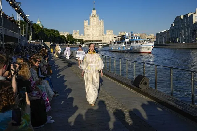 Models display a collection by Russian designer Alena Akhmadullina on Moskvoretskaya embankment during the Fashion Week at Zaryadye Park near Red Square with a Stalin's type skyscraper in the background in Moscow, Russia, Thursday, June 23, 2022. (Photo by Alexander Zemlianichenko/AP Photo)