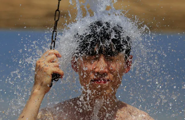 A boy takes a shower after bathing in the Dead Sea, near the West Bank city of Jericho, Sunday, August 16, 2015. The region experienced another heat wave with temperatures in reaching well over 40 degrees Celsius (104 Fahrenheit) in some areas. (Photo by Hatem Moussa/AP Photo)