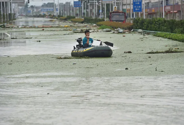 A man paddles through a village in Shucheng county, Anhui, China on July 3, 2016, where four villages have been evacuated after the Fengle river flooded. (Photo by Feature China/Barcroft Images)