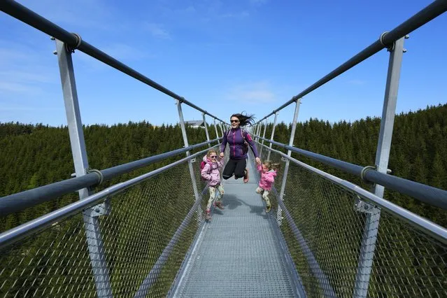 Visitors enjoy a walk accross a suspension bridge for the pedestrians that is the longest such construction in the world shortly after its official opening at a mountain resort in Dolni Morava, Czech Republic, Friday, May 13, 2022. The 721-meter (2,365 feet) long bridge is built at the altitude of more than 1,100 meters above the sea level. It connects two ridges of the mountains up to 95 meters above a valley between them. (Photo by Petr David Josek/AP Photo)