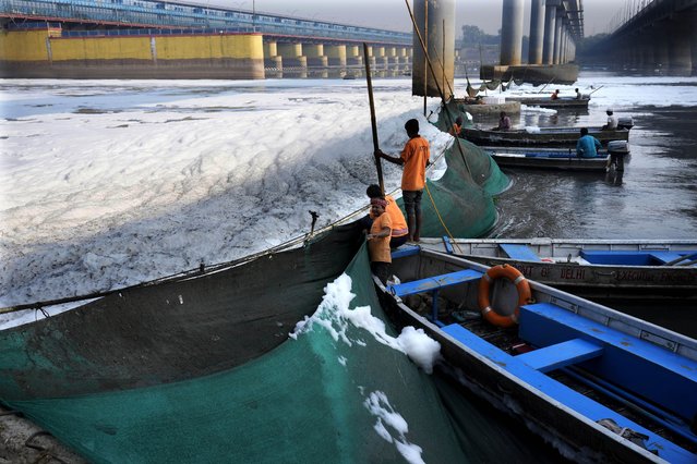Workers for the Delhi Jal or water board put up a cloth curtain to stop the flow of the toxic foams floating in the river Yamuna in New Delhi, India, Tuesday, October 29, 2024. (Photo by Manish Swarup/AP Photo)
